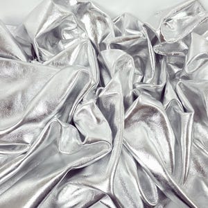 Peut inclure: Un tissu métallique argenté froissé. Le tissu a une surface lisse et brillante et est plié en différentes formes.