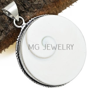 Op de afbeelding: Een ronde, witte hanger met een spiraalvormig ontwerp en een zilverkleurige beugel. De hanger heeft een getextureerde rand en de tekst "MG JEWELRY". De hanger wordt getoond op een stuk hout.