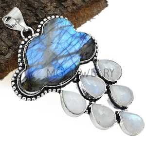 May include: A silver pendant featuring a large blue labradorite gemstone in a cloud shape with a silver bail. Seven smaller white moonstone gemstones are arranged in a teardrop shape below the labradorite.