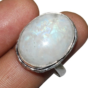 May include: A silver ring featuring a large oval moonstone. The stone has a white iridescent sheen.