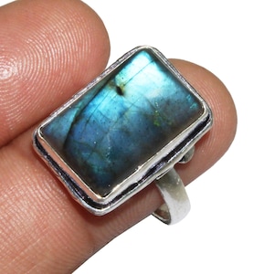 May include: A silver ring with a rectangular blue labradorite gemstone. The ring is set in a silver band with a simple design.