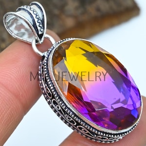Op de afbeelding: Een zilveren hanger met een ovale, gefacetteerde edelsteen. De edelsteen is een gradiënt van geel naar paars. De hanger heeft een sierlijke zilveren bail en een gedetailleerde zilveren rand.