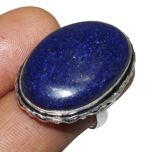 Op de afbeelding: Een zilveren ring met een grote ovale lapis lazuli-edelsteen. De steen is diepblauw met gouden vlekken.