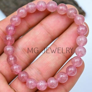 May include: A pink quartz beaded bracelet with a light pink hue. The bracelet is made of round beads and is approximately 7 inches in length.