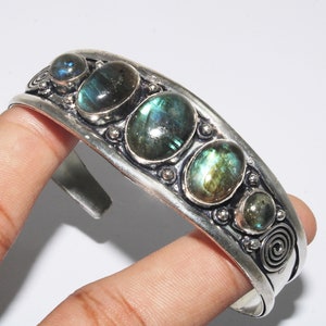 Pode incluir: Pulseira de bracelete de prata com cinco pedras ovaladas de labradorita. A pulseira tem um design texturizado e uma abertura com dobradiça.