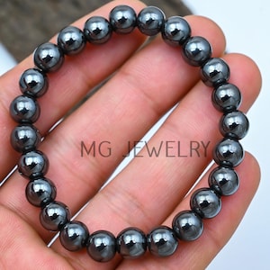 May include: A black hematite beaded bracelet with a shiny finish. The bracelet is made of round beads and is approximately 7.5 inches in length.