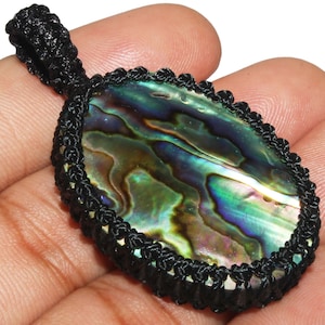 Può includere: Ciondolo ovale in madreperla di abalone con un cordoncino nero e un bordo annodato.