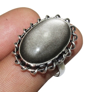 May include: A silver ring with an oval-shaped black gemstone set in a decorative silver frame.