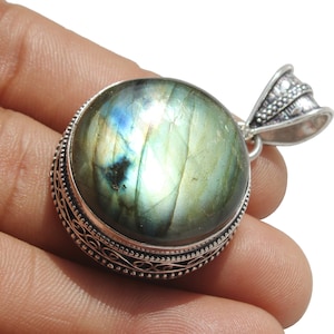 May include: A silver pendant with a large, round, green labradorite gemstone set in an ornate silver bezel. The pendant has a silver bail for attaching to a chain.