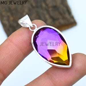 May include: A silver pendant with a teardrop-shaped purple and yellow gemstone.