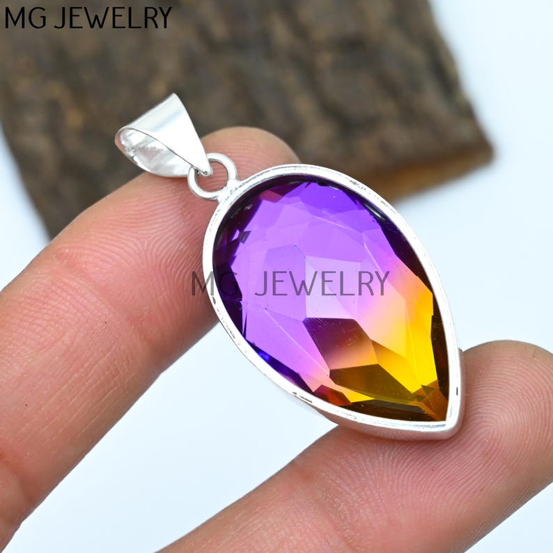 May include: A silver pendant with a teardrop-shaped purple and yellow gemstone.