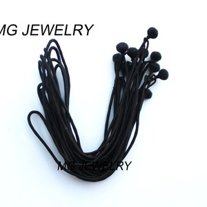 May include: A bundle of black elastic cord with small black ball ends. The cord is approximately 10 inches long.