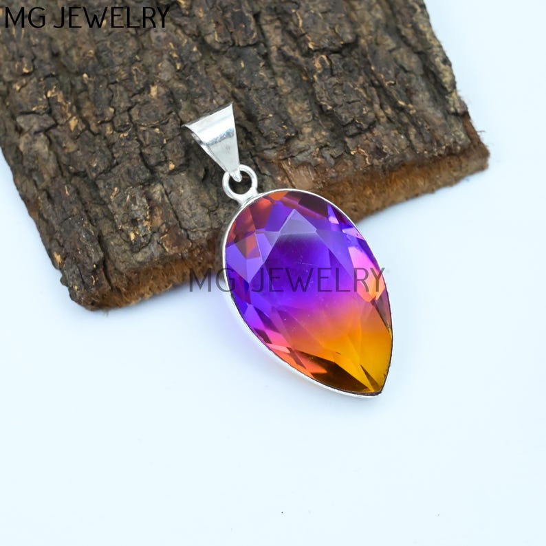 May include: A pearlescent teardrop pendant with a gradient of purple to orange. The pendant is made of silver and has a smooth, polished finish.
