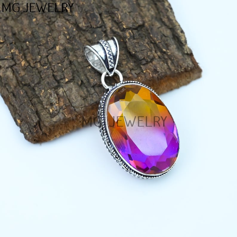 May include: A silver pendant with an oval-shaped, iridescent gemstone. The gemstone is a gradient of yellow, orange, and purple. The pendant has a detailed silver design around the gemstone.