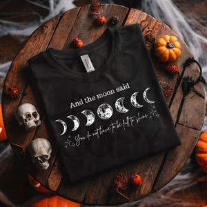 May include: Black t-shirt with a white graphic of a crescent moon and the text "And the moon said You do not have to be full to shine."