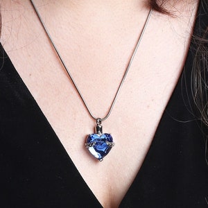 May include: A silver chain necklace with a blue crystal heart pendant.