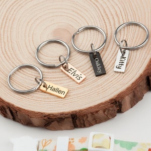 May include: Four silver keychains with personalized engraved tags. The tags read "Kitty", "Oakley", "Elvis", and "Hallen".