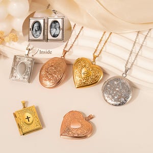 May include: A collection of various metal lockets on chains. The lockets are in different shapes, including oval, heart, and book-shaped, and in colors like gold, silver, and rose gold. Some lockets have engraved floral patterns, while others have a cross or a heart-shaped cutout.