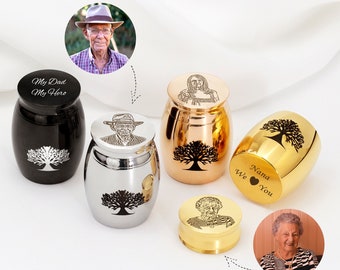 Puede incluir: Una colección de urnas conmemorativas en negro, plateado, dorado y oro rosa. Cada urna presenta un diseño de árbol de la vida y grabados personalizados, incluyendo retratos y textos como "My Dad My Hero" y "Nana We You".