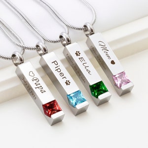 May include: Four silver bar necklaces with different colored gemstones and engraved messages. The necklaces are engraved with the names "Mom", "Ella", "Piper", and "Papa". The messages on the necklaces are "Always in my Heart", "Forever by my side", and "July 25 1955".