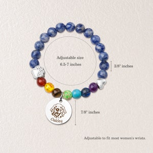 May include: A blue gemstone bracelet with a rainbow of smaller gemstones, a paw print charm, and a heart charm. The bracelet has a round charm with a dog's face and the name "Oakley" engraved on it. The bracelet is adjustable from 6.5 to 7 inches and the charm is 7/8 inches in diameter.