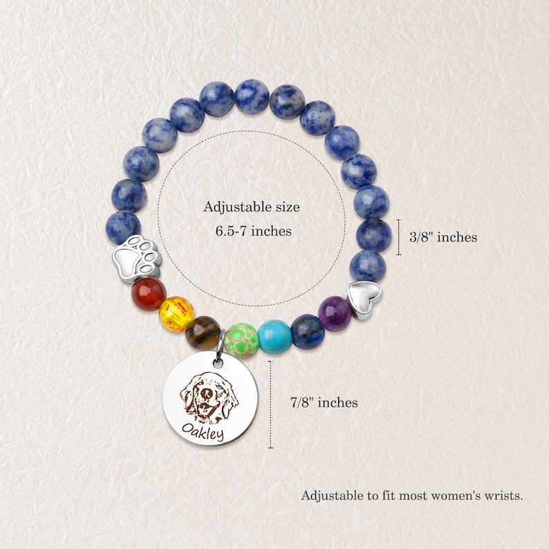 May include: A blue gemstone bracelet with a rainbow of smaller gemstones, a paw print charm, and a heart charm. The bracelet has a round charm with a dog's face and the name "Oakley" engraved on it. The bracelet is adjustable from 6.5 to 7 inches and the charm is 7/8 inches in diameter.