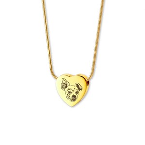May include: Gold heart-shaped pendant necklace with an engraved image of a dog. The necklace is on a gold chain.