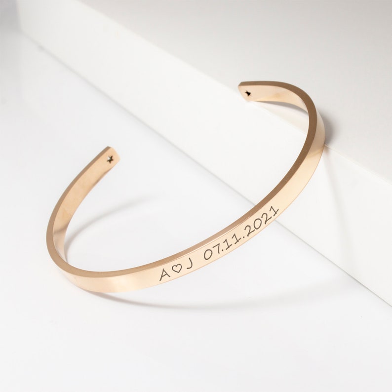 Op de afbeelding: Een gouden armband met een gegraveerde inscriptie "A&hearts;J 07.11.2021".