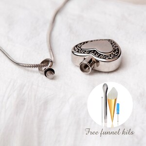 May include: Silver heart-shaped cremation necklace with a chain. The necklace comes with a small funnel and screwdriver for filling the pendant.