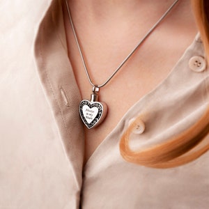 Puede incluir: Un collar de plata con un colgante en forma de coraz&oacute;n con la inscripci&oacute;n "Always in my heart".