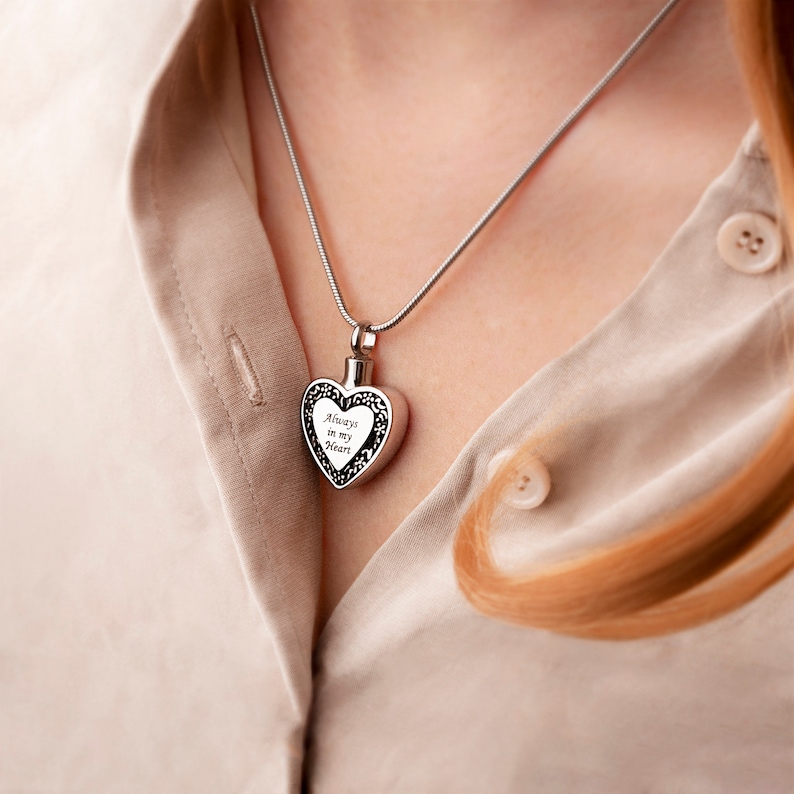 Puede incluir: Un collar de plata con un colgante en forma de coraz&oacute;n con la inscripci&oacute;n "Always in my heart".