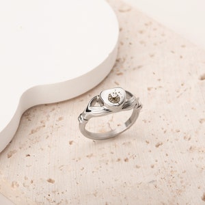 May include: A silver ring featuring a heart-shaped design. The heart is filled with a delicate dandelion design.