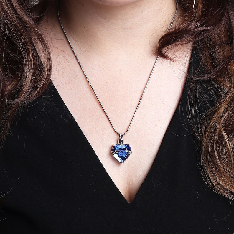 May include: A silver chain necklace with a blue crystal heart pendant.