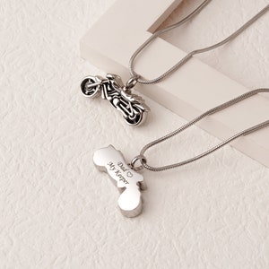 Puede incluir: Dos collares de plata con colgantes de motocicleta. Un colgante es un dise&ntilde;o de motocicleta detallado, mientras que el otro tiene las palabras "Dad My Keeper" grabadas.