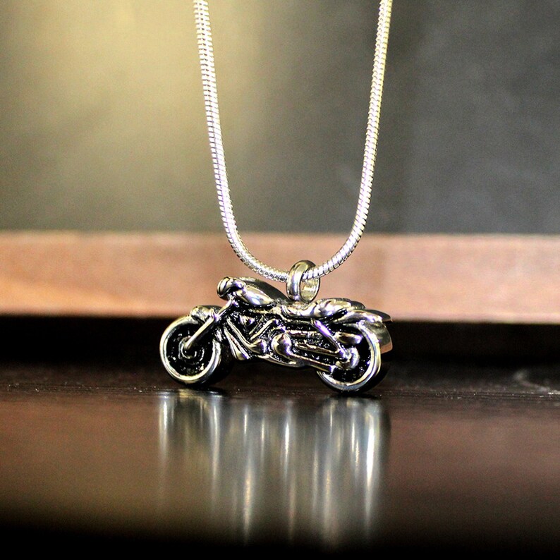 Puede incluir: Un collar de cadena de plata con un colgante de motocicleta de plata. La motocicleta est&aacute; detallada y tiene un dise&ntilde;o realista.