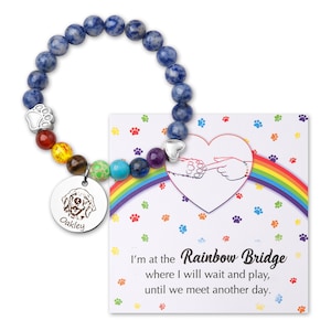 May include: A blue gemstone bracelet with a rainbow of smaller gemstones and a silver charm with a paw print. The bracelet comes with a card that reads "I'm at the Rainbow Bridge where I will wait and play, until we meet another day."