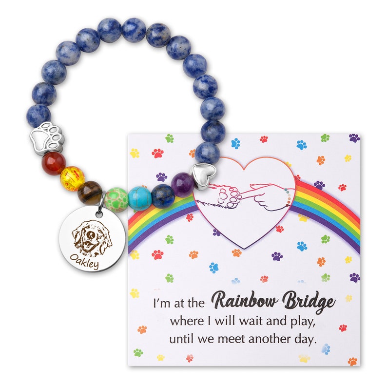 May include: A blue gemstone bracelet with a rainbow of smaller gemstones and a silver charm with a paw print. The bracelet comes with a card that reads "I'm at the Rainbow Bridge where I will wait and play, until we meet another day."