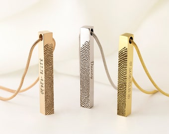 Könnte beinhalten: Drei personalisierte Bar-Halsketten in Gold, Silber und Roségold. Jeder Anhänger zeigt einen Fingerabdruck und gravierten Text. Die Halsketten hängen an zarten Schlangenkettchen und präsentieren ein einzigartiges und sentimentales Design.