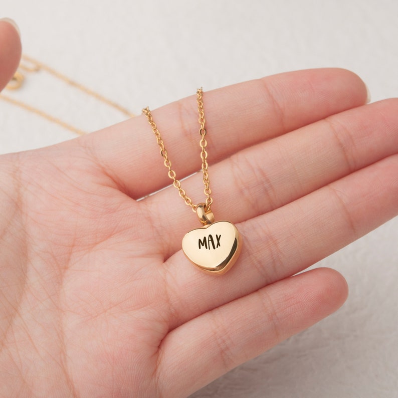 May include: Gold heart-shaped pendant necklace with the name "MAX" engraved on it.