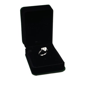 May include: A silver heart-shaped ring with a small inscription inside the heart. The ring is in a black velvet ring box.