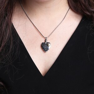 May include: A silver heart-shaped pendant necklace with a gold heart charm. The pendant has an inscription that reads "In loving memory of a life well lived".