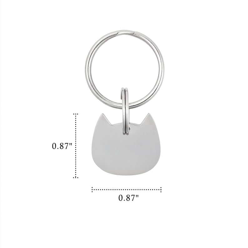 Puede incluir: Una placa de metal plateado con forma de cabeza de gato unida a una anilla circular. La placa tiene una superficie lisa y en blanco, y mide 2,21 cm de alto por 2,21 cm de ancho, tal como indican las l&iacute;neas de dimensi&oacute;n visibles en la imagen.