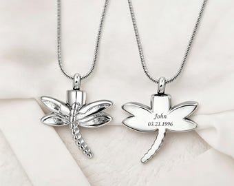 May include: Two silver dragonfly pendant necklaces. One dragonfly pendant is detailed with etched wings and body segments. The other pendant has the name "John" and the date "03.21.1996" engraved on the wings.