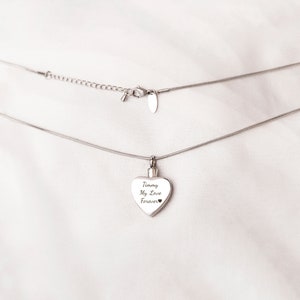 May include: A silver chain necklace with a heart-shaped pendant. The pendant has the inscription "Timmy My Love Forever" on it.