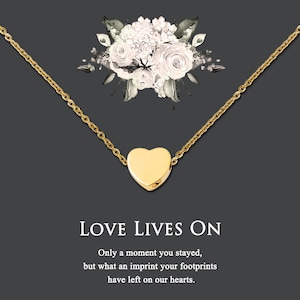 Puede incluir: Un collar de oro con un peque&ntilde;o colgante en forma de coraz&oacute;n. El collar est&aacute; sobre un fondo gris con un dise&ntilde;o floral. El texto "LOVE LIVES ON" est&aacute; debajo del collar, seguido de la cita "Only a moment you stayed, but what an imprint your footprints have left on our hearts."