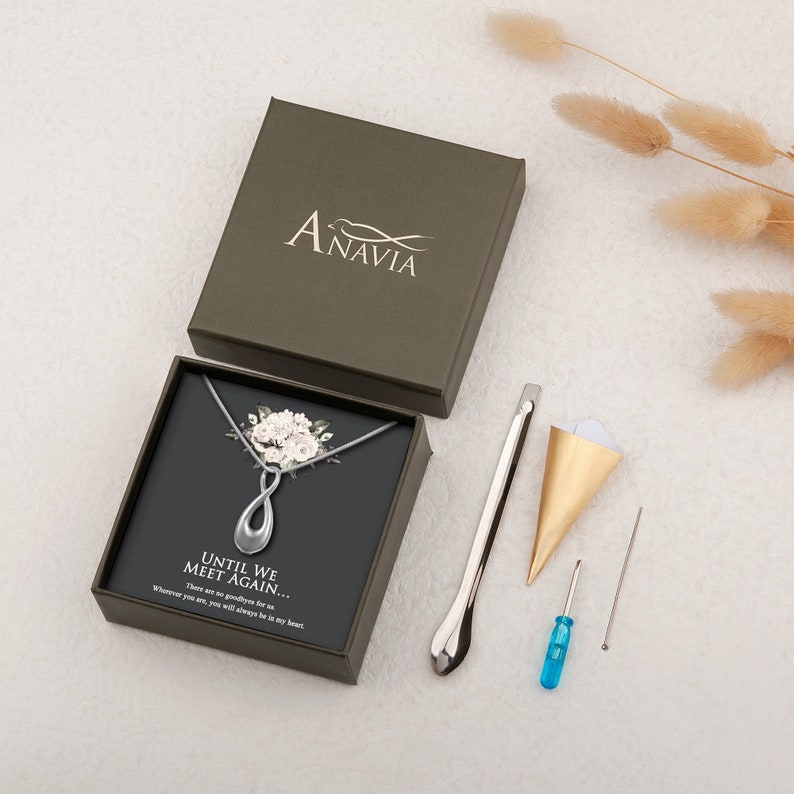 May include: A silver necklace with an infinity symbol pendant and a floral design. The necklace comes in a black box with a white background and the text "Until we meet again... There are no goodbyes for us... Wherever you are, you will always be in my heart."