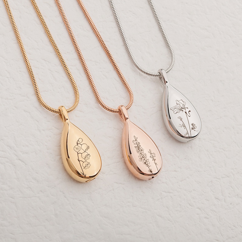 May include: Three silver, gold, and rose gold necklaces with teardrop-shaped pendants. Each pendant features a delicate engraved floral design.