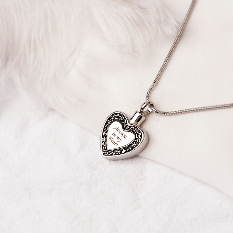 Puede incluir: Collar de cremaci&oacute;n en forma de coraz&oacute;n plateado con una cadena. El coraz&oacute;n tiene una inscripci&oacute;n que dice "Always in my Heart".