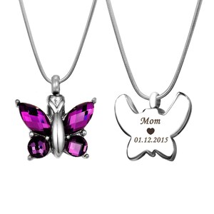 May include: A silver butterfly cremation necklace with purple crystal accents. The pendant has a removable compartment for ashes. The back of the pendant is engraved with the words "Mom" and "01.12.2015".