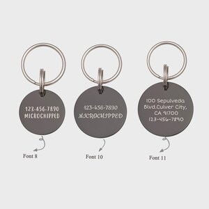 Op de afbeelding: Drie zilveren sleutelhangers met ronde zwarte labels. De labels hebben verschillende lettertypen en tekst. Het eerste label zegt "123-456-7890 MICROCHIPPED" in een klein lettertype. Het tweede label zegt "123-456-7890 MICROCHIPPED" in een iets groter lettertype. Het derde label zegt "100 Sepulveda Blvd.Culver City, CA 91700 123-456-7890" in een groter lettertype.